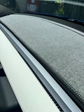 Interior view of a Tesla vehicle showing the dashboard with a carpeted dash mat in a neutral color, designed to protect the dash from UV radiation and heat.