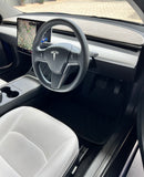 Interior view of a Tesla vehicle showing the dashboard with a carpeted dash mat in a neutral color, designed to protect the dash from UV radiation and heat.